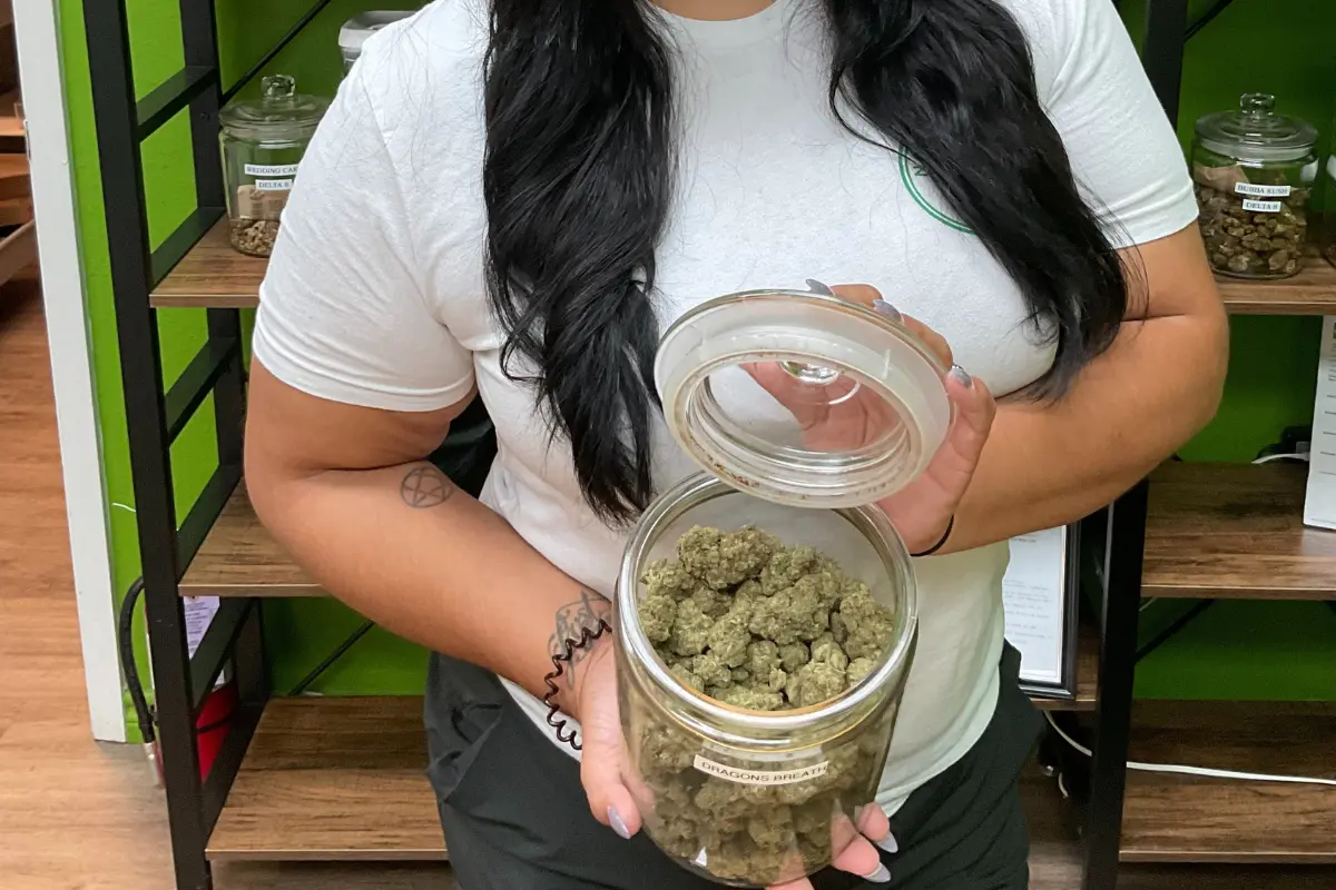 Woman holding jar of hemp flower. 