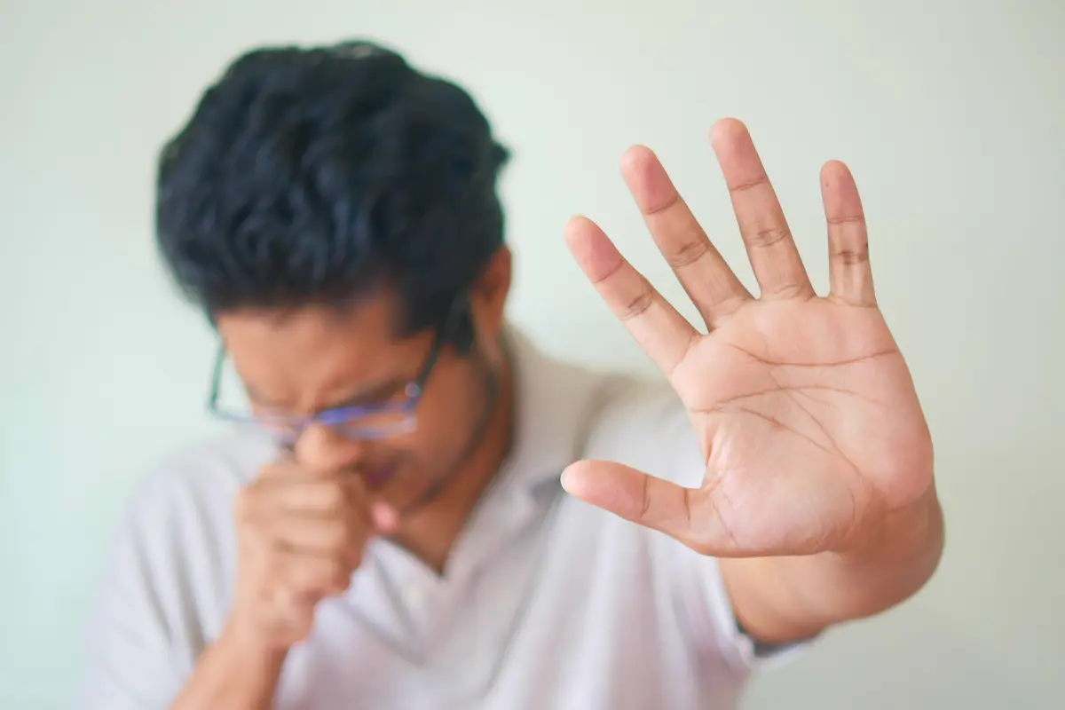 Man with sore throat coughing and putting hand up