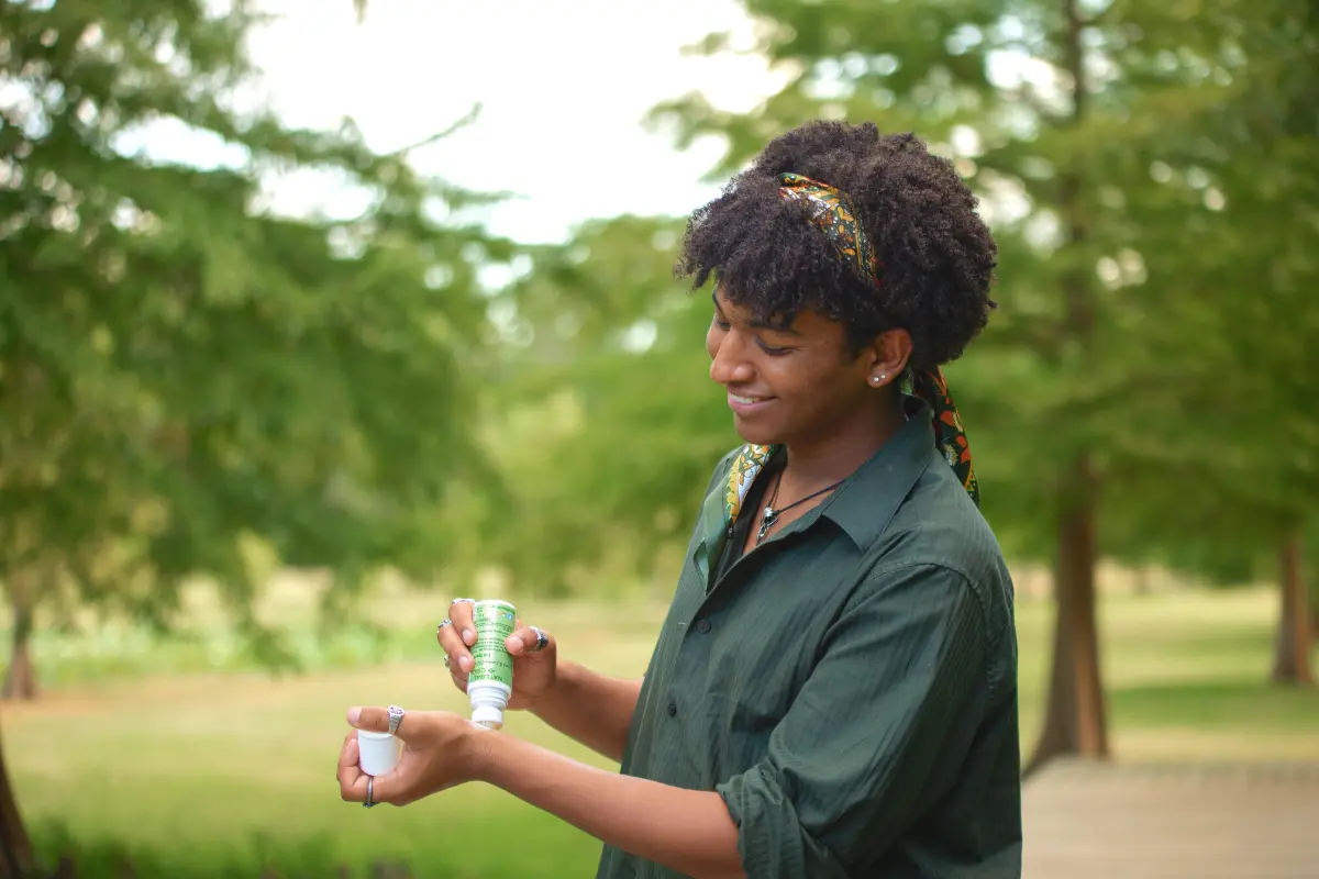 Young man applying Natural Ways CBD CBD roll-on topical product to arm. 